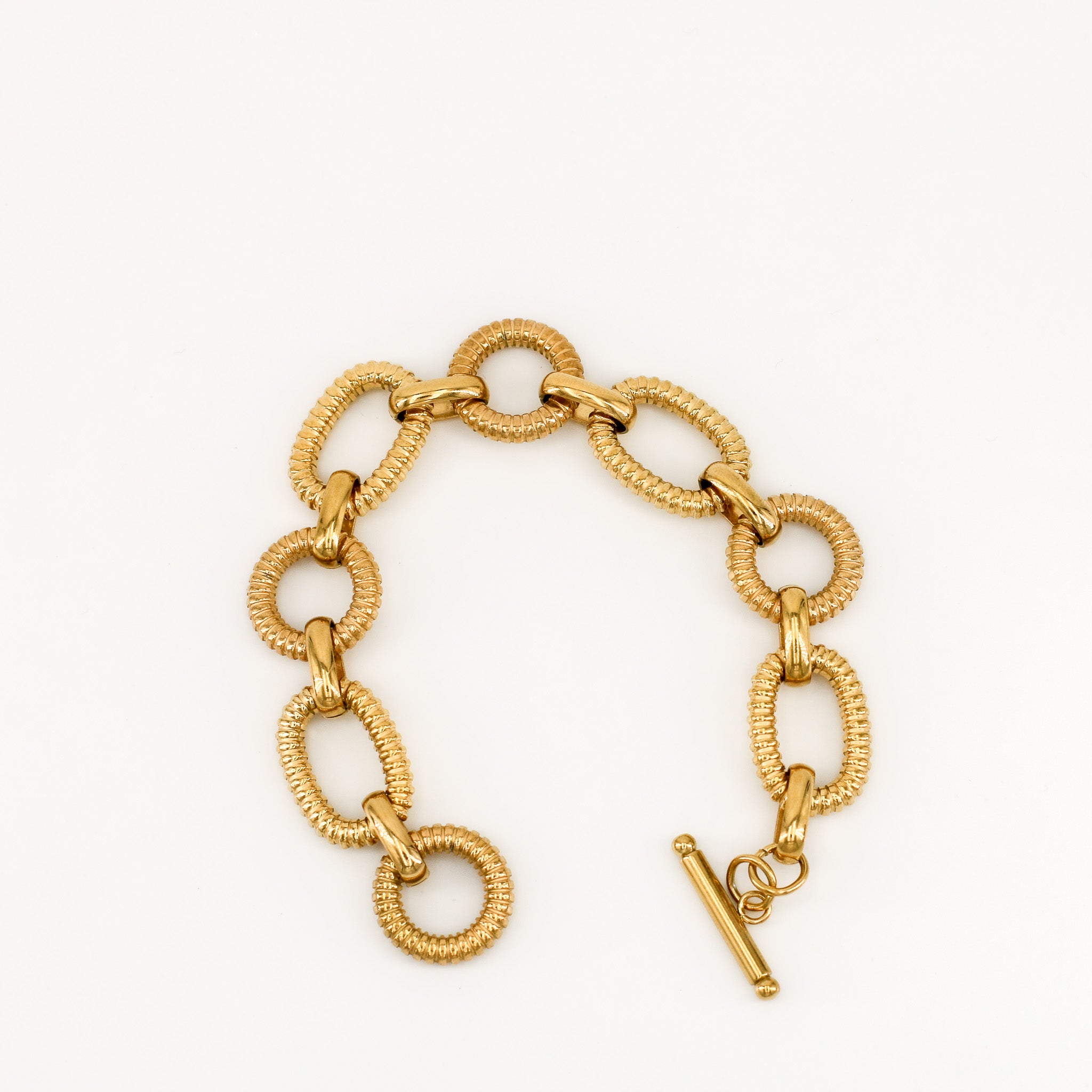 Vergoldetes Armband mit strukturierten Gliedern und T-Verschluss auf hellem Hintergrund.