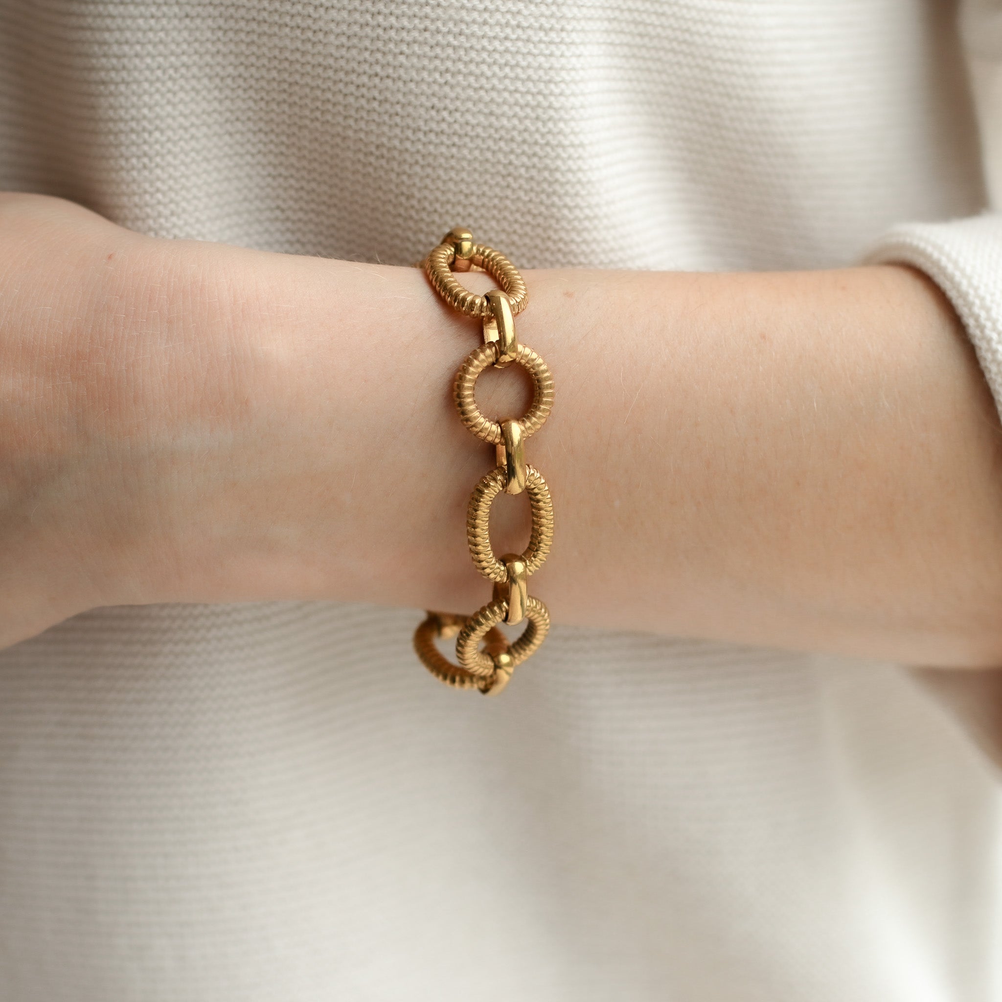 Detailaufnahme eines vergoldeten Armbands mit eleganter Struktur.