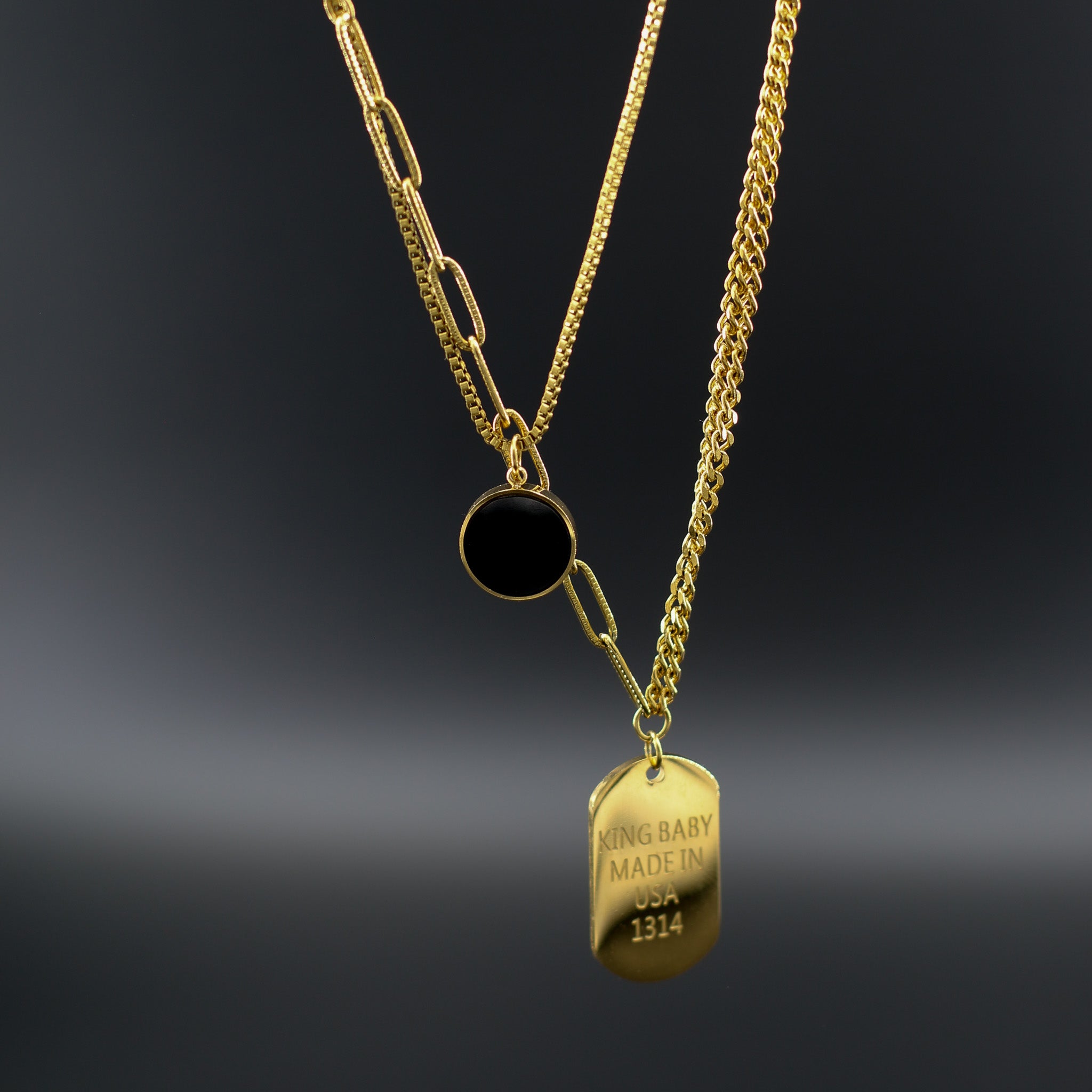 Mehrlagige Kette 'Tri-Chain Vibes' auf einem Dekolleté, mit schwarzem Stein-Anhänger, Medaillon und vergoldeten Ketten, gefertigt aus 316L Edelstahl.